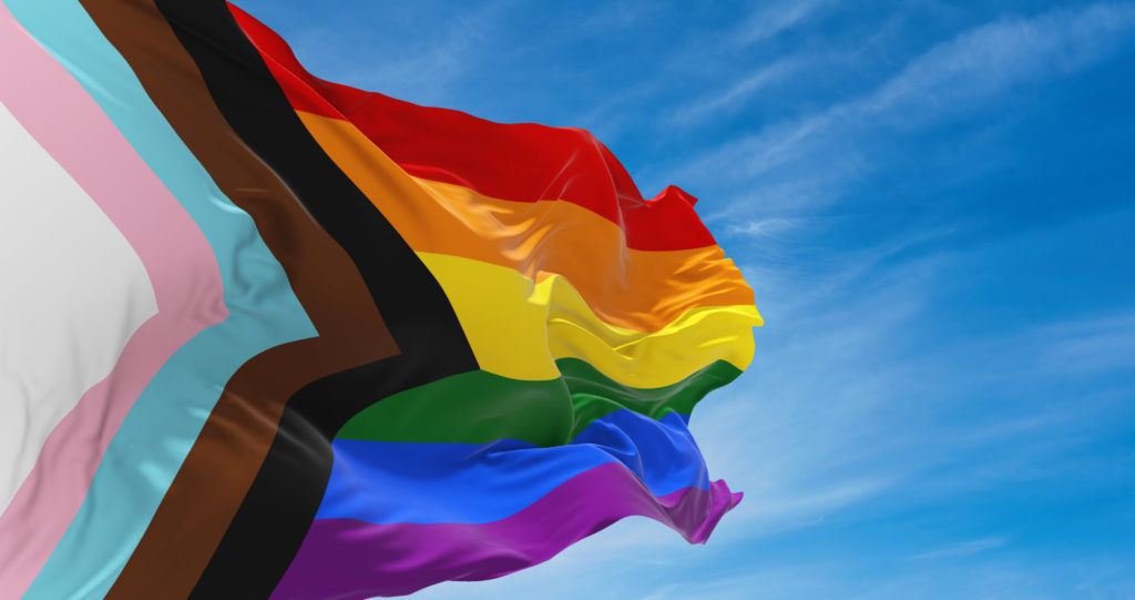 Progress LGBTQ rainbow flag waving in the wind at cloudy sky. Freedom and love concept. Pride month. activism, community and freedom Concept. Copy space. 3d illustration.