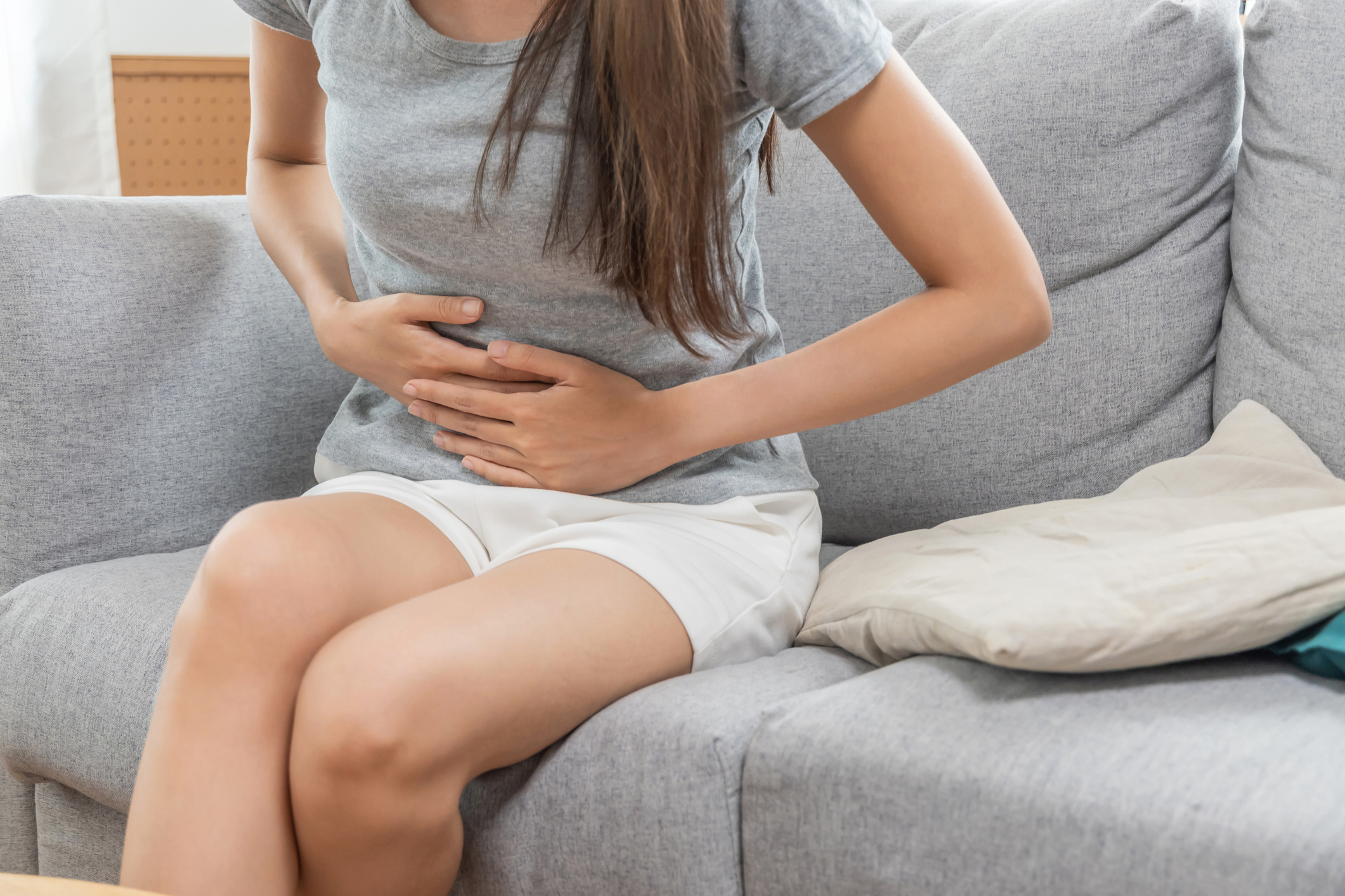 Young woman holding stomach on couch