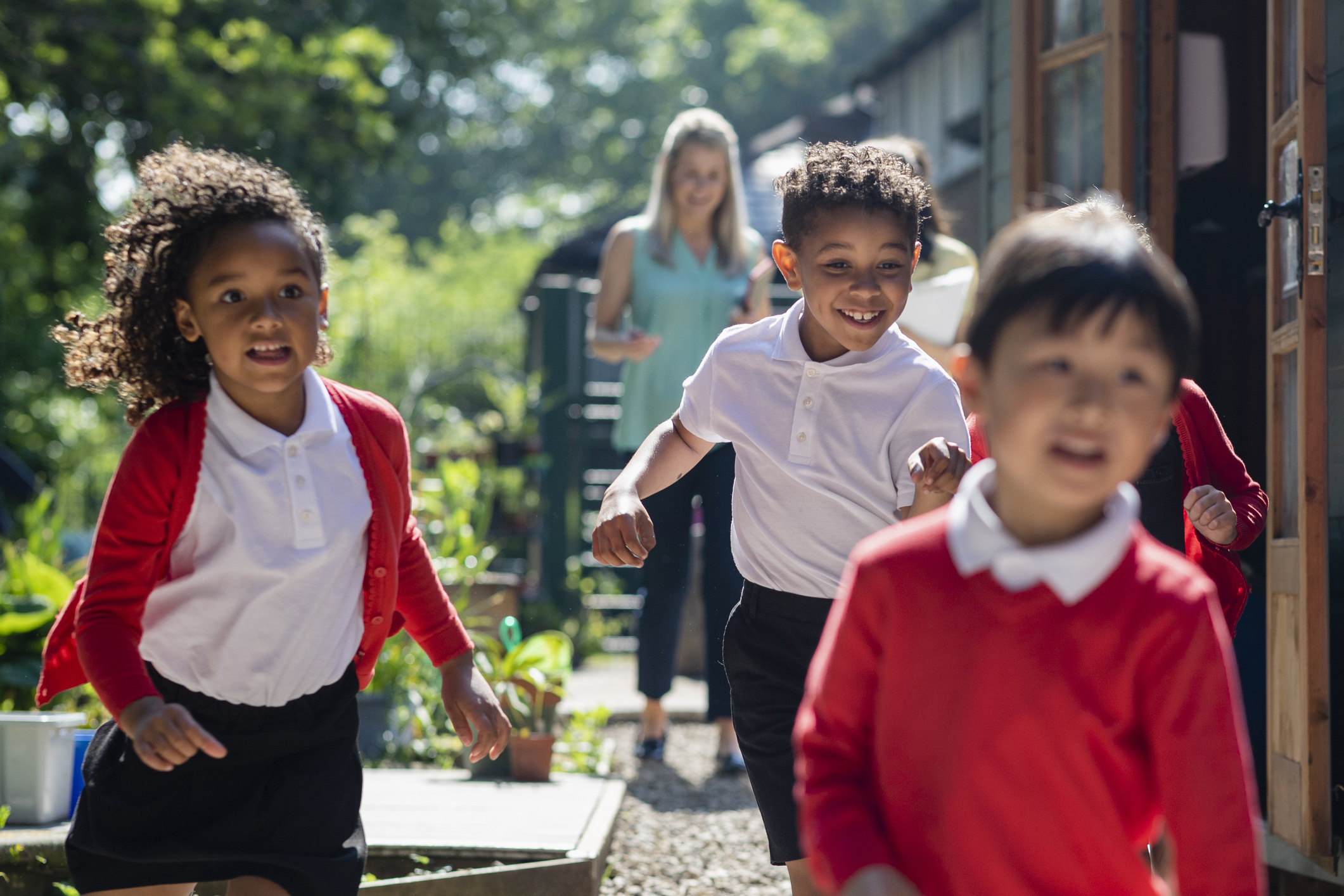 Kids running outside with educator in background