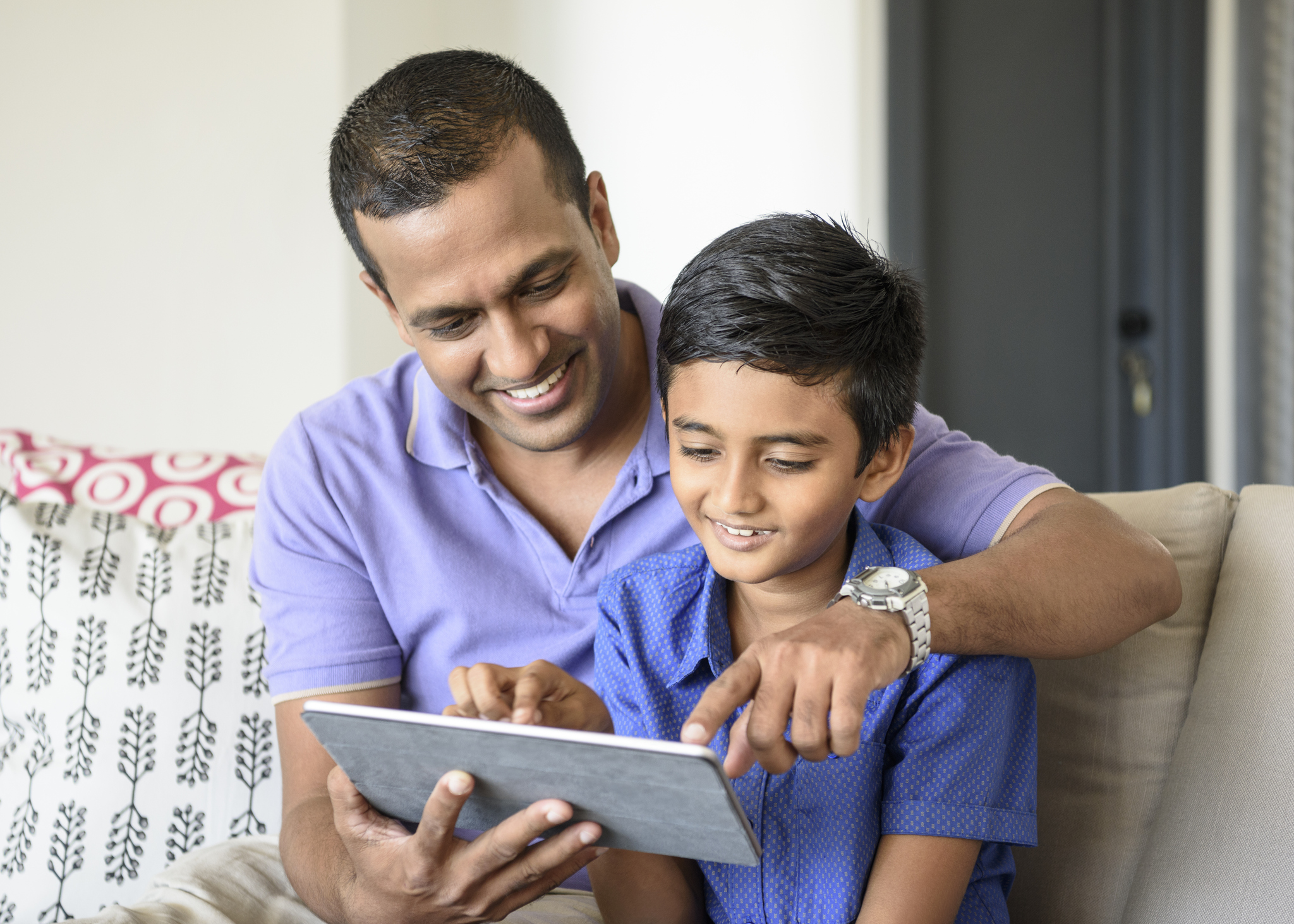 Father and son on sofa using a tablet